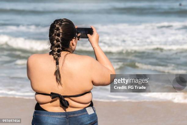 plus size woman photographing the beach - chubby swimsuit stock pictures, royalty-free photos & images