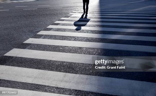 man walking across large intersection. - 人行過路線 個照片及圖片檔