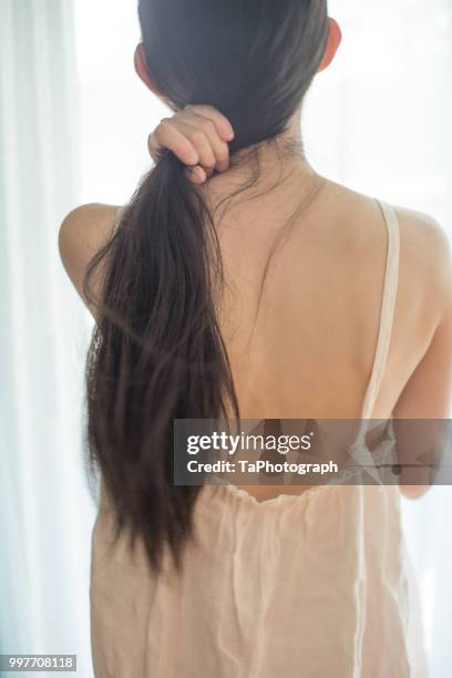 woman binding her hair at the back - damaged hair stock pictures, royalty-free photos & images