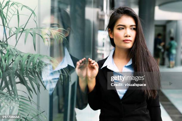 一個年輕的亞洲婦女靠在玻璃牆上的肖像。 - vanguardians 個照片及圖片檔