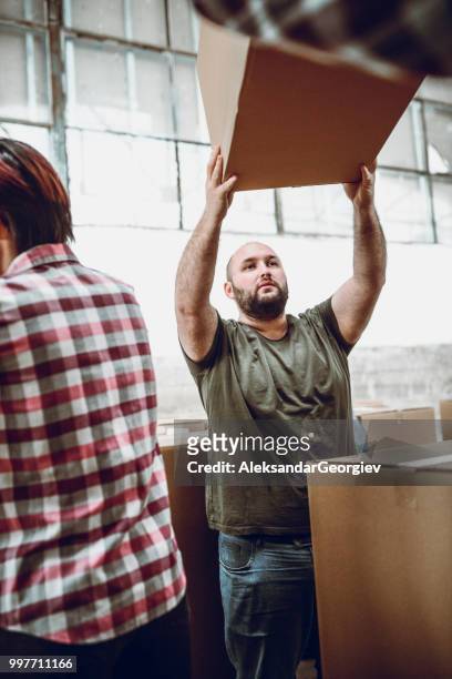 männliche arbeiter in fabrik anheben box bereit für verpackungen - aleksandar georgiev stock-fotos und bilder