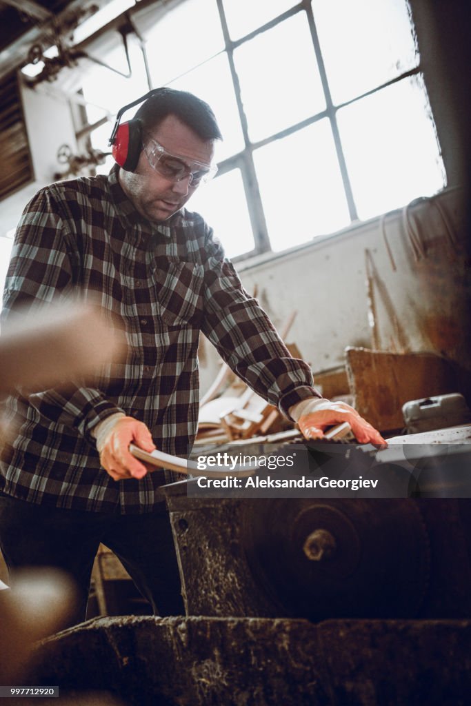 Male Carpenter Sawing Through Chair Handle