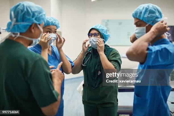 artsen voorbereiding voor een operatie in het ziekenhuis - operatiegewaad stockfoto's en -beelden