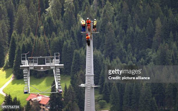 Assemblers of a specialist company wait for a part of a cable car support which will be transported to them by a helicopter at the Ifen in the...