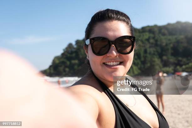 plus größe frau nimmt ein selfie am strand - dicke frauen am strand stock-fotos und bilder