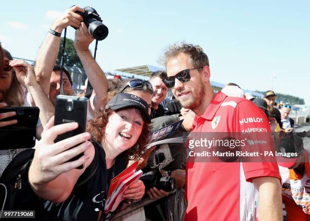 Scuderia Ferrari driver Sebastian Vettel poses for photographs with the crowd on paddock day of the 2018 British Grand Prix at Silverstone Circuit,...