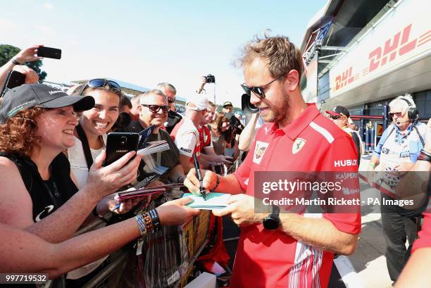 Scuderia Ferrari driver Sebastian Vettel poses for photographs with the crowd on paddock day of the 2018 British Grand Prix at Silverstone Circuit,...