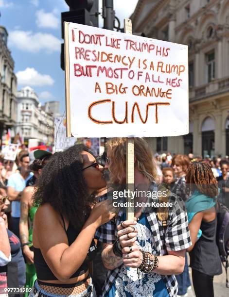 Demonstrators share a kis while holding Anti Trump Placard attend the Drag Protest Parade LGBTQi March against Trump on July 13, 2018 in London,...