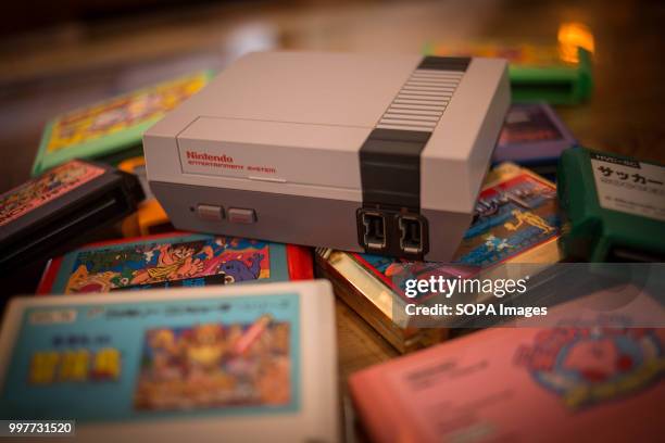 In this photo illustration, a Nintendo Classic Mini 'Nintendo Entertainment System' video game console first generation seen with a pile of Famicom...