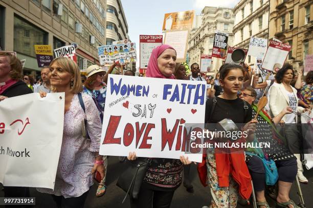 Protesters against the UK visit of US President Donald Trump hold up placards as they take part in a march and rally in London on July 13, 2018. -...