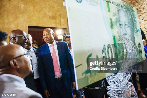 Lesetja Kganyago, governor of South Africa's reserve bank, center, and Nhlanhla Nene, South Africa's finance minister, inspect a display of...