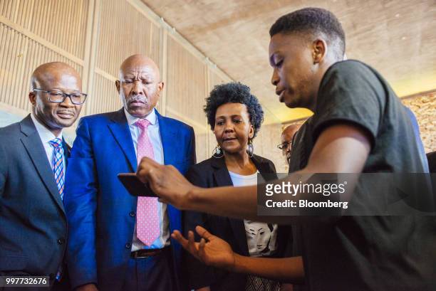 Lesetja Kganyago, governor of South Africa's reserve bank, second left, inspects a mobile phone app in Pretoria, South Africa, on Friday, July 13,...