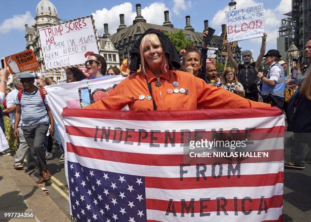 Protesters against the UK visit of US President Donald Trump hold up flags and placards as they take part in a march and rally in London on July 13,...