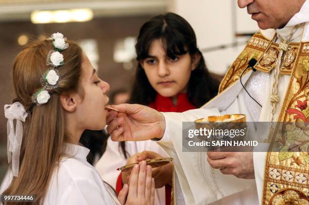 An Iraqi Chaldean Christian girl receives her First Communion during mass at the Apostles Peter and Paul Chaldean Catholic Church in Arbil, the...