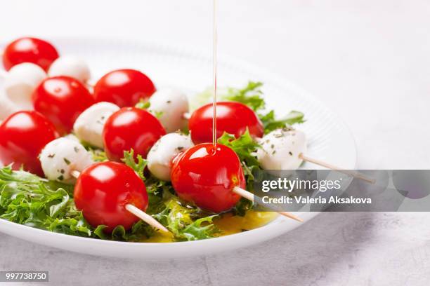 tomatoes and mozzarella on sticks on salad leaves, closeup - side salad fotografías e imágenes de stock