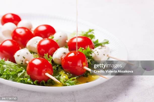 tomatoes and mozzarella on sticks on salad leaves, closeup - side salad - fotografias e filmes do acervo