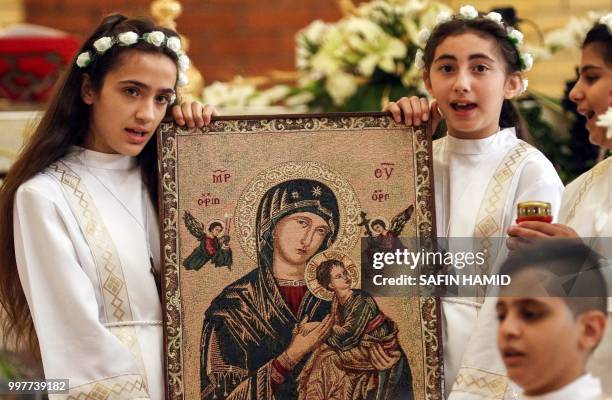 Iraqi Chaldean Christian children hold up an "Eleusa" icon, depicting the Virgin Mary holding up the infant Jesus nestled under her cheek, as they...