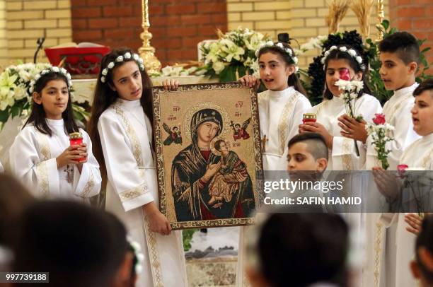 Iraqi Chaldean Christian children hold up an "Eleusa" icon, depicting the Virgin Mary holding up the infant Jesus nestled under her cheek, as they...