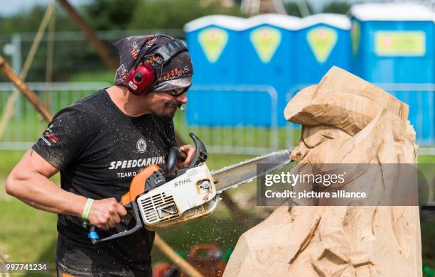 Winfried Breunig carves with a chainsaw a bust out of a piece of wood at the festival grounds of the Wacken Open Air festival in Wacken, Germany, 02...