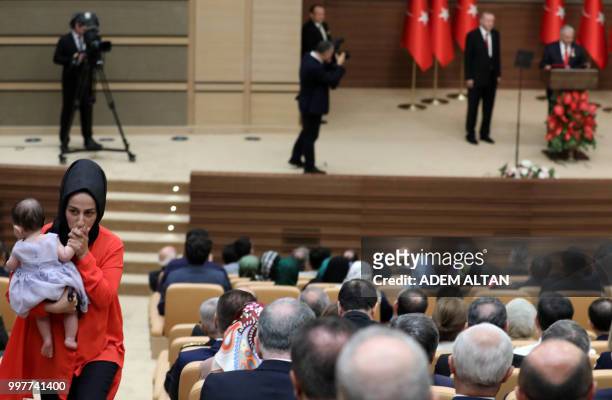 Woman holds a child as Turkey's President Recep Tayyip Erdogan looks on while Turkish Grand National Assembly Speaker Binali Yildirim makes a speech...