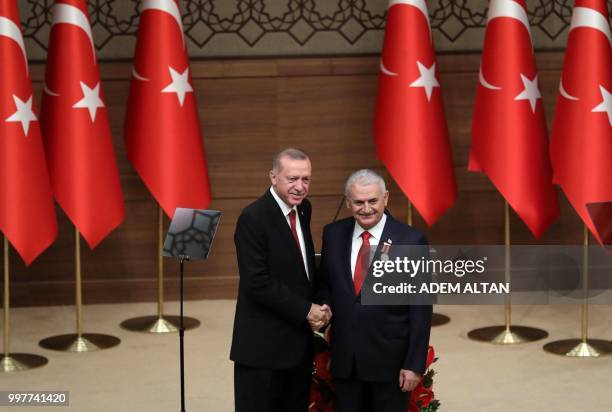 Turkey's President Recep Tayyip Erdogan shakes hands with Turkish Grand National Assembly Speaker Binali Yildirim after investing him with an Order...