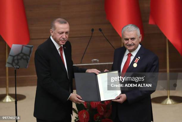 Turkey's President Recep Tayyip Erdogan poses with an Order of Merit certificate and Turkish Grand National Assembly Speaker Binali Yildirim after...