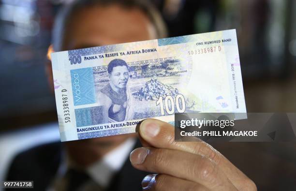 Man holds a new South African banknote at the value of one hundred South African Rand depicting former South African president Nelson Mandela at The...