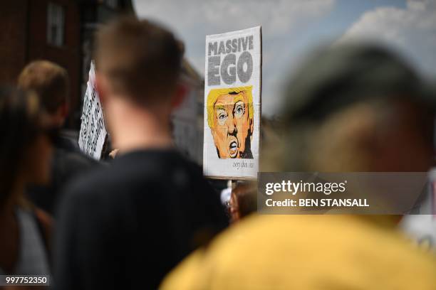 Protesters against the visit of US President Donald Trump carry placards outside Windsor Castle in Windsor, west of London, on July 13, 2018 where...