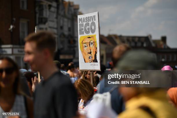 Protesters against the visit of US President Donald Trump carry placards outside Windsor Castle in Windsor, west of London, on July 13, 2018 where...