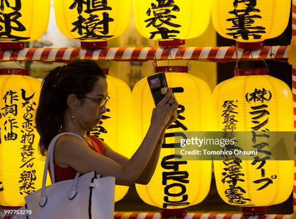 Woman takes a photograph of lit paper lanterns during the Mitama Matsuri summer festival at the Yasukuni Shrine on July 13, 2018 in Tokyo, Japan. The...