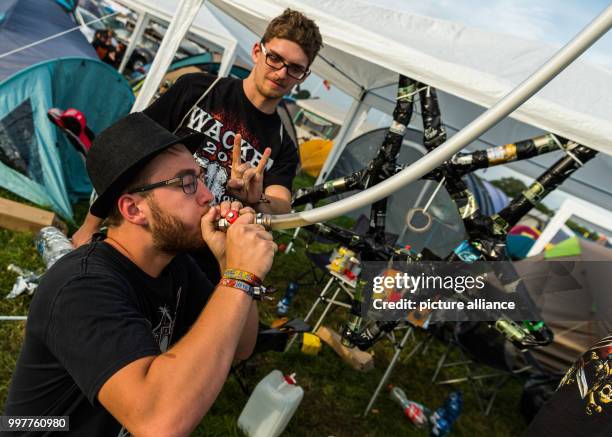 Peter from Austria drinks beer out of a hose while his friend Marc gives the universal metal sign at the Wacken Open Air festival in Wacken, Germany,...