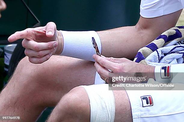 Mens Singles, Semi-Final - Kevin Anderson v John Isner - John Isner blows on a finger injury at All England Lawn Tennis and Croquet Club on July 13,...