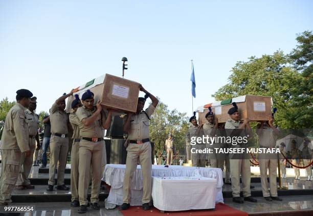 Indian paramilitary troopers carry the coffins of slain colleagues during a wreath laying ceremony at a paramilitary camp in Srinagar on July 13,...