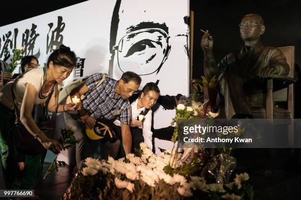 Vigil participants lay flowers in front of statue of Liu Xiaobo during a memorial vigil held for Chinese Nobel Peace Prize-winner Liu Xiaobo on July...