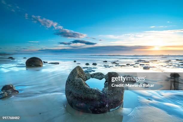 sunrise over otago coastline, south island, new ze - moeraki boulders ストックフォトと画像