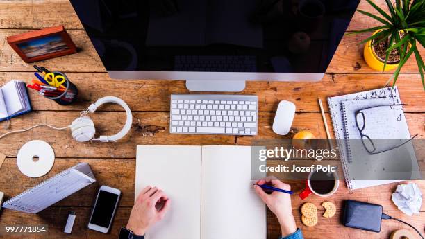 business person working at office desk holding a notebook - desk toy stock pictures, royalty-free photos & images