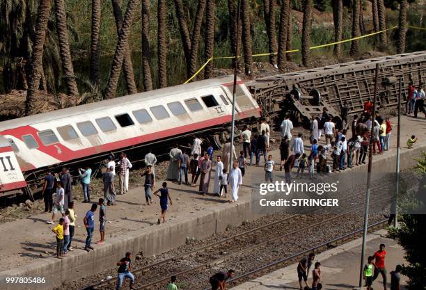 Egyptians gather by the train tracks to look at the scene of a railway accident as a a train derailed near Badrasheen, a town some 20 kilometres from...