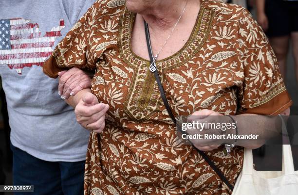 An elderly woman is helped stepping off a curb at a Fourth of July holiday event in Santa Fe, New Mexico.