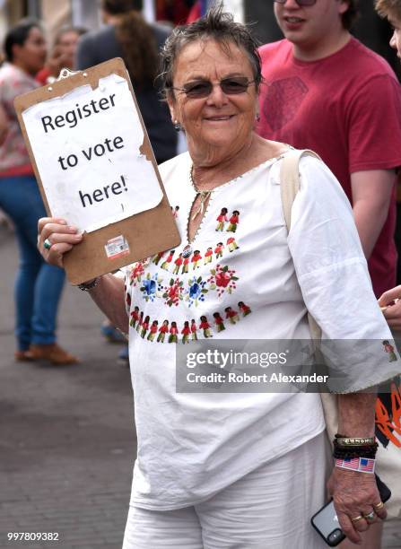 Volunteer looks for people interested in registering to vote as she circulates at a Fourth of July holiday event in Santa Fe, New Mexico.