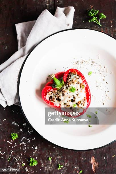 top view of baked in the oven red bell pepper stuffed with minced pork and beef meat, covered with melted cheese, served with fresh parsley in a plate on a wooden table. comfort food. picnic food. - roasted pepper ストックフォトと画像