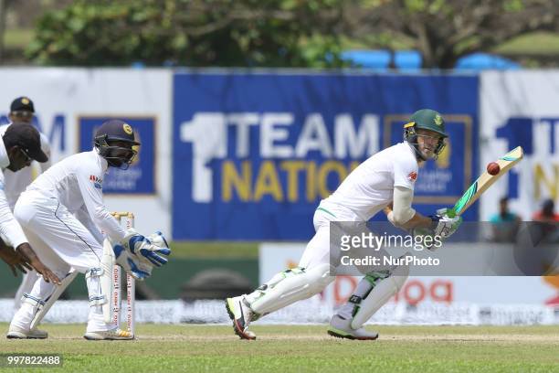 South African captain Faf Du Plessis plays a shot as Sri Lankan wicketkeeper Niroshan Diskwella looks on during the 2nd day's play in the first Test...