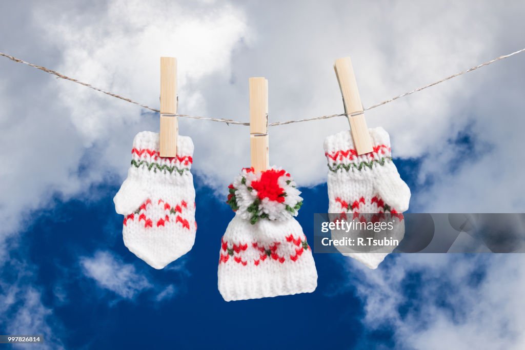 Hat and pair of gloves drying in the open air hanging on clothes line affixed with wooden pegs