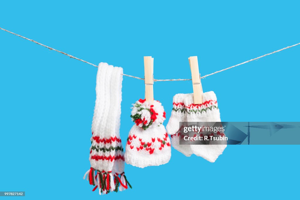 Hat, scarf and pair of gloves drying in the open air hanging on clothes line affixed with wooden pegs