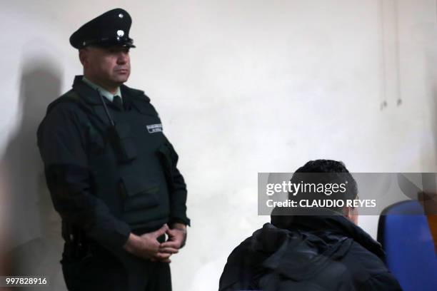 Policemnan stands next to Chilean priest Oscar Munoz Toledo at a courtroom in Rancagua, 80 km south of Santiago, Chile, on July 13, 2018. - Prominent...