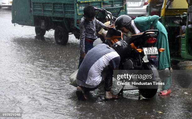 Family stuck in water logged road near Nizamuddin during the heavy rain, on July 13, 2018 in New Delhi, India. The heavy rains came as a respite to...