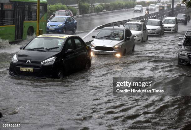 Vehicles wade through the water logged road near Nizamuddin during the heavy rain, on July 13, 2018 in New Delhi, India. The heavy rains came as a...