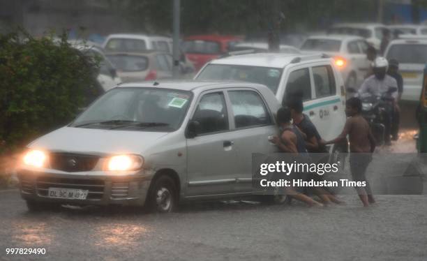 Commuters wade through a water-logged road due to heavy rainfall, at Ranjit Flyover, on July 13, 2018 in New Delhi, India. The heavy rains came as a...