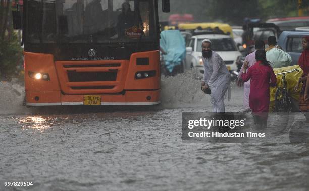 Commuters wade through a water-logged road due to heavy rainfall, at Ranjit Flyover, on July 13, 2018 in New Delhi, India. The heavy rains came as a...