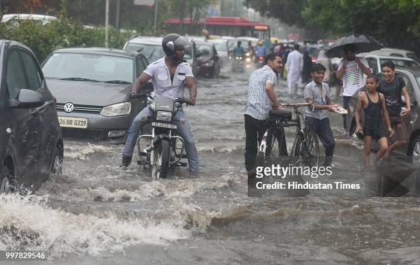 Commuters wade through a water-logged road due to heavy rainfall, at Ranjit Flyover, on July 13, 2018 in New Delhi, India. The heavy rains came as a...