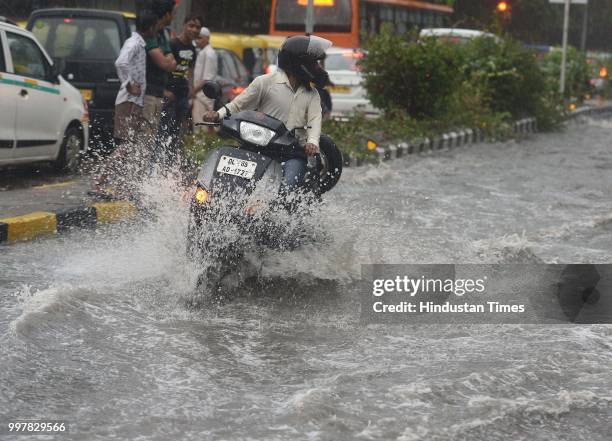 Commuters wade through a water-logged road due to heavy rainfall, at Ranjit Flyover, on July 13, 2018 in New Delhi, India. The heavy rains came as a...